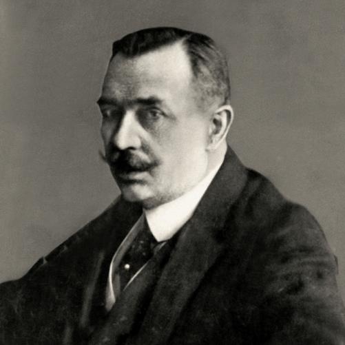 Maurycy Zamoyski - półprofil mężczyzny z bujnym wąsem, ciemnymi włosami, ciemna marynarka, ciemny krawat, biała koszula.