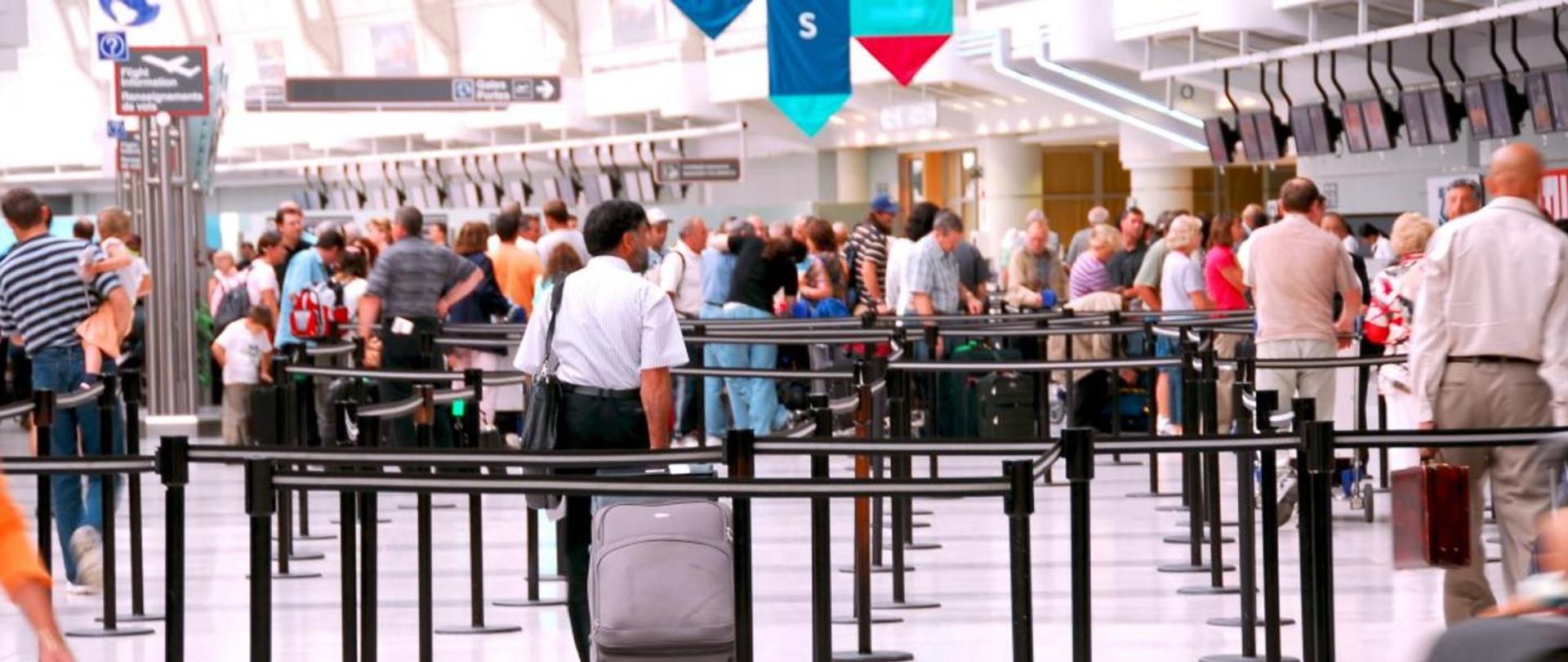 Pasażerowie stojący w kolejkach do odprawy w terminalu lotniczym