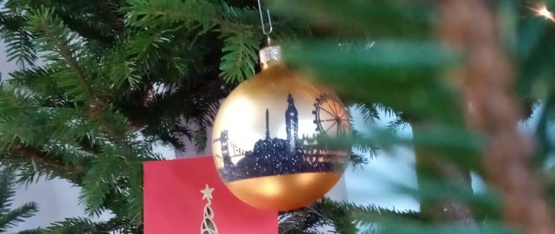 Choinka Bożonarodzeniowa, na której leży kartka z życzeniami Pomorskiego Komendanta Wojewódzkiego Państwowej Straży Pożarnej oraz bombka z widokiem Gdańska