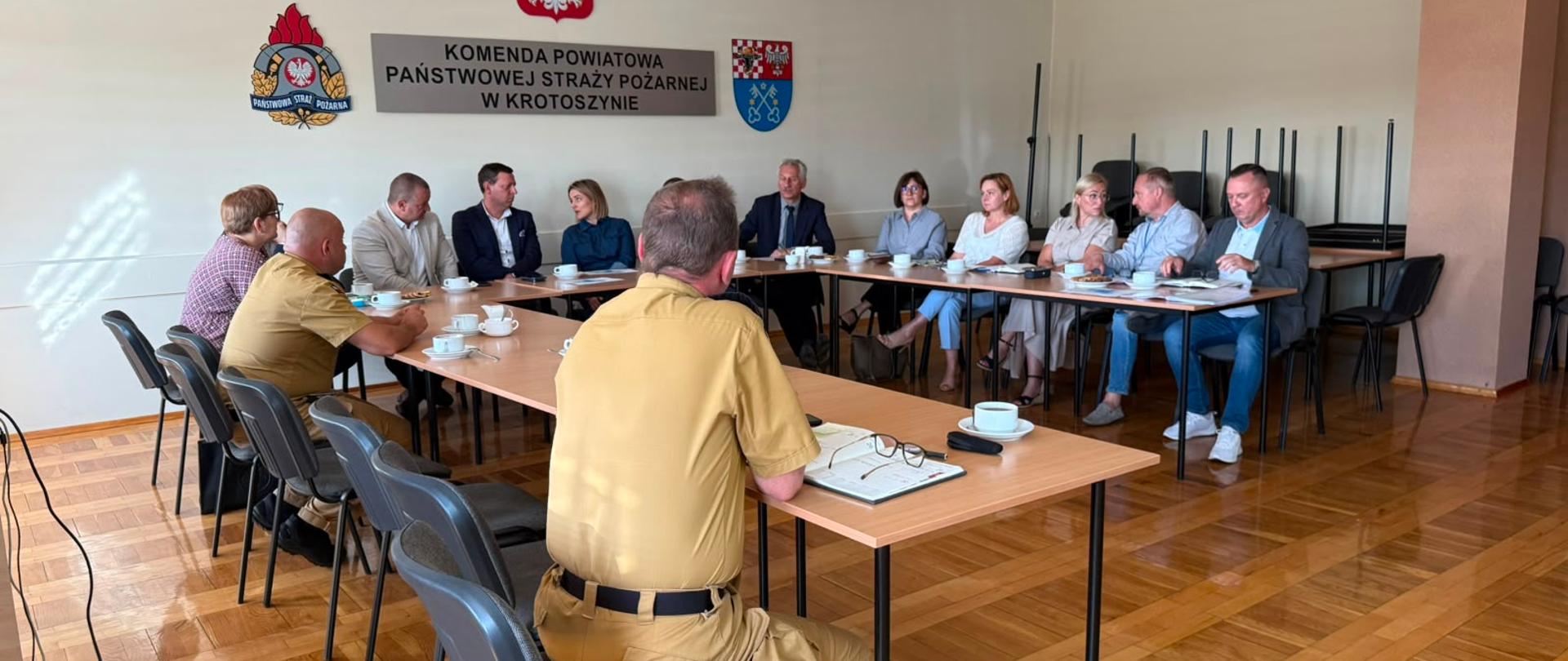 Zdjęcie przedstawia samorządowców oraz komendanta w sali konferencyjnej.
