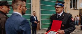 Widok z tyłu. Komendant Powiatowy PSP wręcza podziękowanie Burmistrzowi Wadowic. W tle Poseł na Sejm RP Filip Kaczyński oraz pracownicy Komendy. 