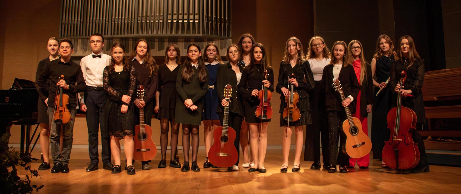 Grupowe zdjęcie uczniów stojących na scenie i pozujących do wspólnego zdjęcia