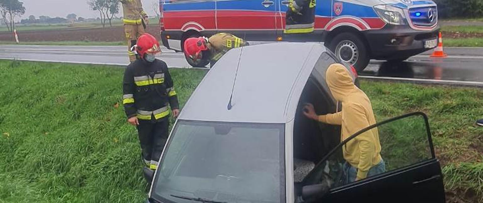 Samochód osobowy stoczył się do przydrożnego rowu. W tle karetka pogotowia.
