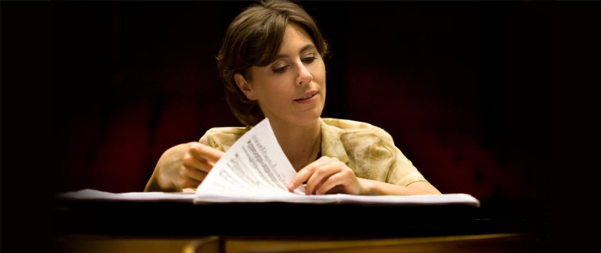 Zdjęcie przedstawia Urszulę Szyryńską przeglądającą nuty przy fortepianie