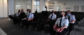 Przedstawiciele Państwowej Straży Pożarnej i ochotniczych straży pożarnych siedzą i słuchają.