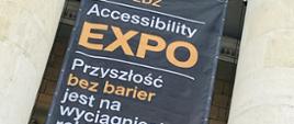 Fragment fasady pałacu kultury i nauki w Warszawie, pomiędzy dwoma kolumnami z głowicami kompozytowymi rozpięty jest Baner z napisem: odwiedzić Accessibility Expo – przyszłość bez barier jest na wyciągnięcie ręki