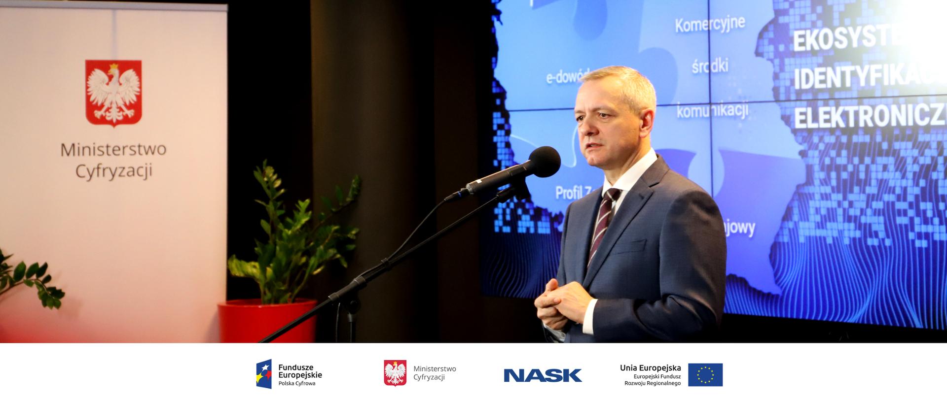 Minister Marek Zagórski na konferencji prasowej. W tle plansza z napisem Ekosystem Identyfikacji Elektronicznej.