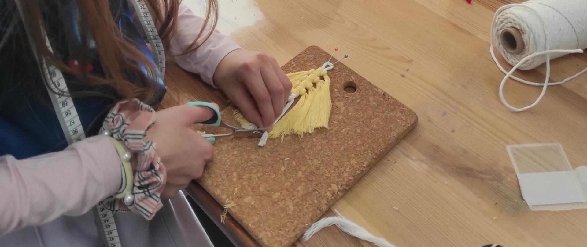 Na zdjęciu dzieci pracują i tworzą makramowe zawieszki