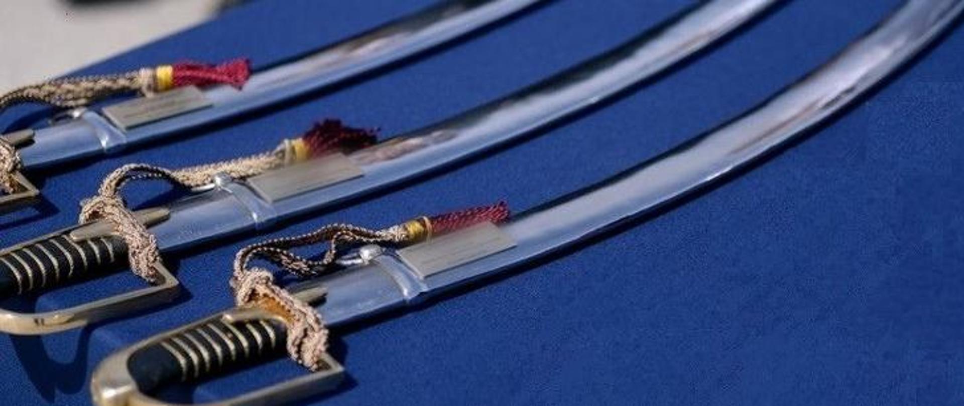 trzy szable generalskie leżące na niebieskim suknie
