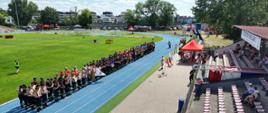 Powiatowe Zawody Sportowo-Pożarnicze, zawodnicy ustawieni na bieżni stadiony na zbiórce, podczas uroczystego rozpoczęcia zawodów, Goście oraz kibice 