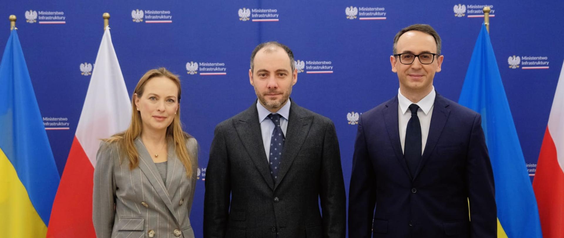 Trzy osoby stoją obok siebie. Pierwsza od lewej stoi minister Katarzyna Pełczyńska-Nalęcz.