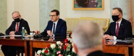 Minister Adam Niedzielski, premier Mateusz Morawiecki i prezydent Andrzej Duda siedzą przy stole.