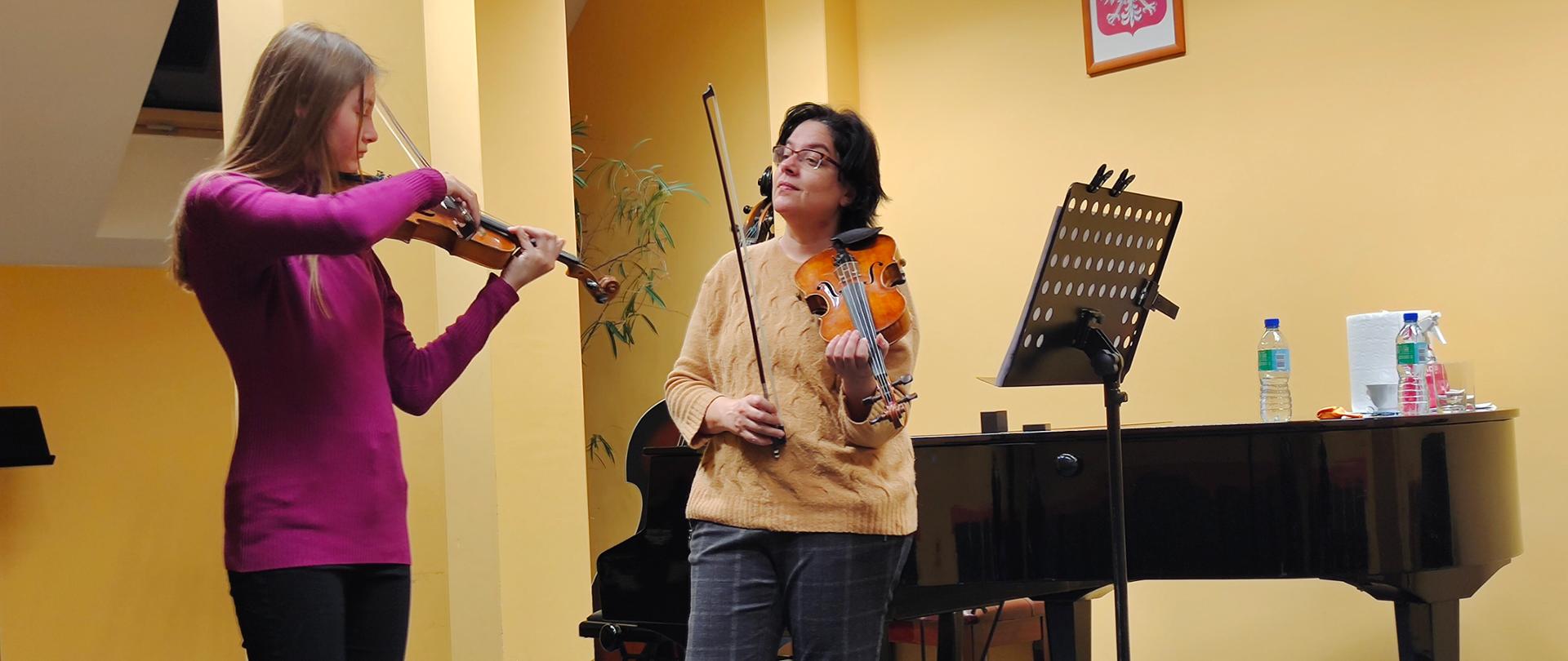 Zdjęcie przedstawia nauczyciela i ucznia podczas lekcji gry na skrzypcach