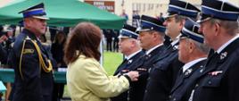 Zdjęcie zrobione podczas uroczystości. Wicewojewoda Podkarpacki przypina odznaczenie do munduru druha Ochotniczej Straży Pożarnej. Obok stoi oficer Państwowej Straży Pożarnej w stopniu starszego brygadiera. 