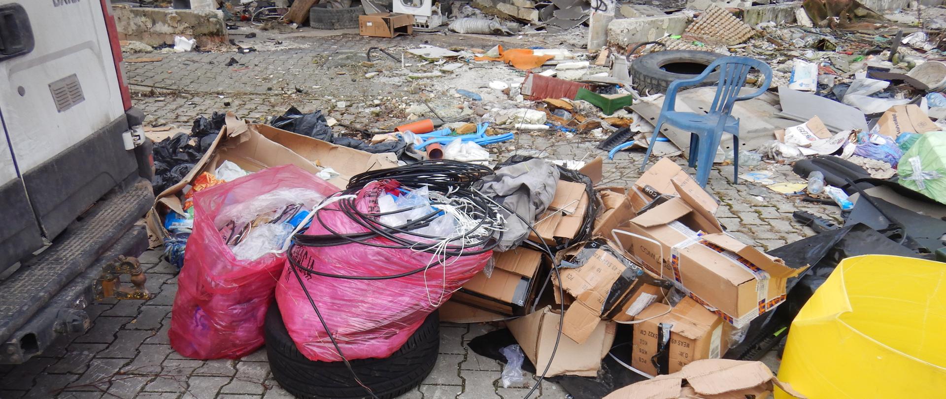 Rozrzucone worki foliowe z kablami, kartony i fragmenty plastiku 