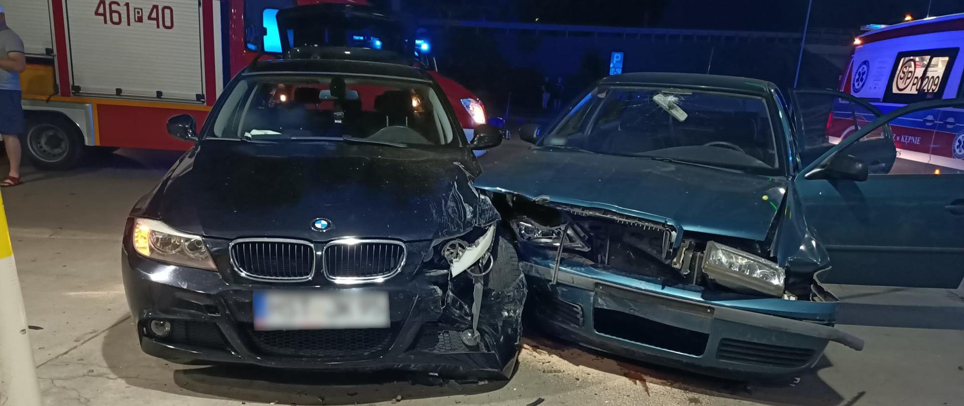 Widoczne miejsce zdarzenia, uszkodzone pojazdy biorące udział w kolizji, gapie oraz pojazdy służb ratowniczych.