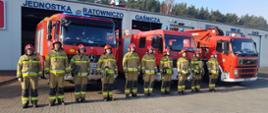 Strażacy stojąc na baczność na tle samochodów gaśniczych oddają cześć poległym strażakom z Ukrainy.