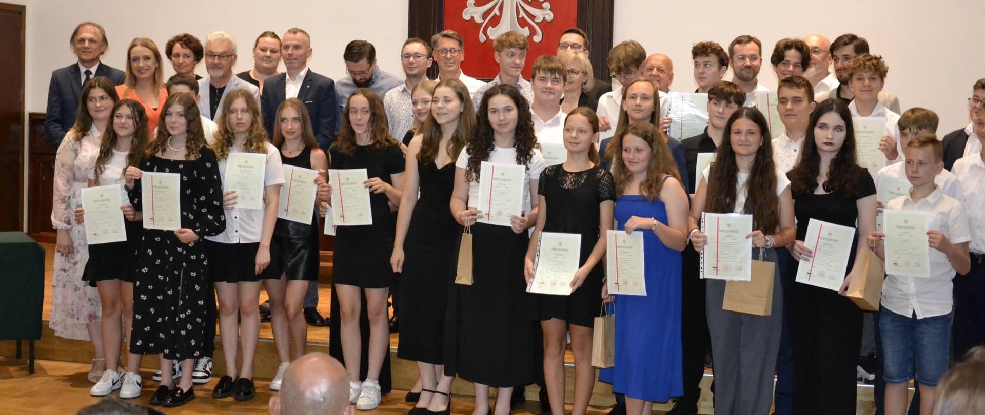 Absolwenci PSM I stopnia zgromadzeni wraz z nauczycielami na scenie Sali Królewskiej PSM Mielec