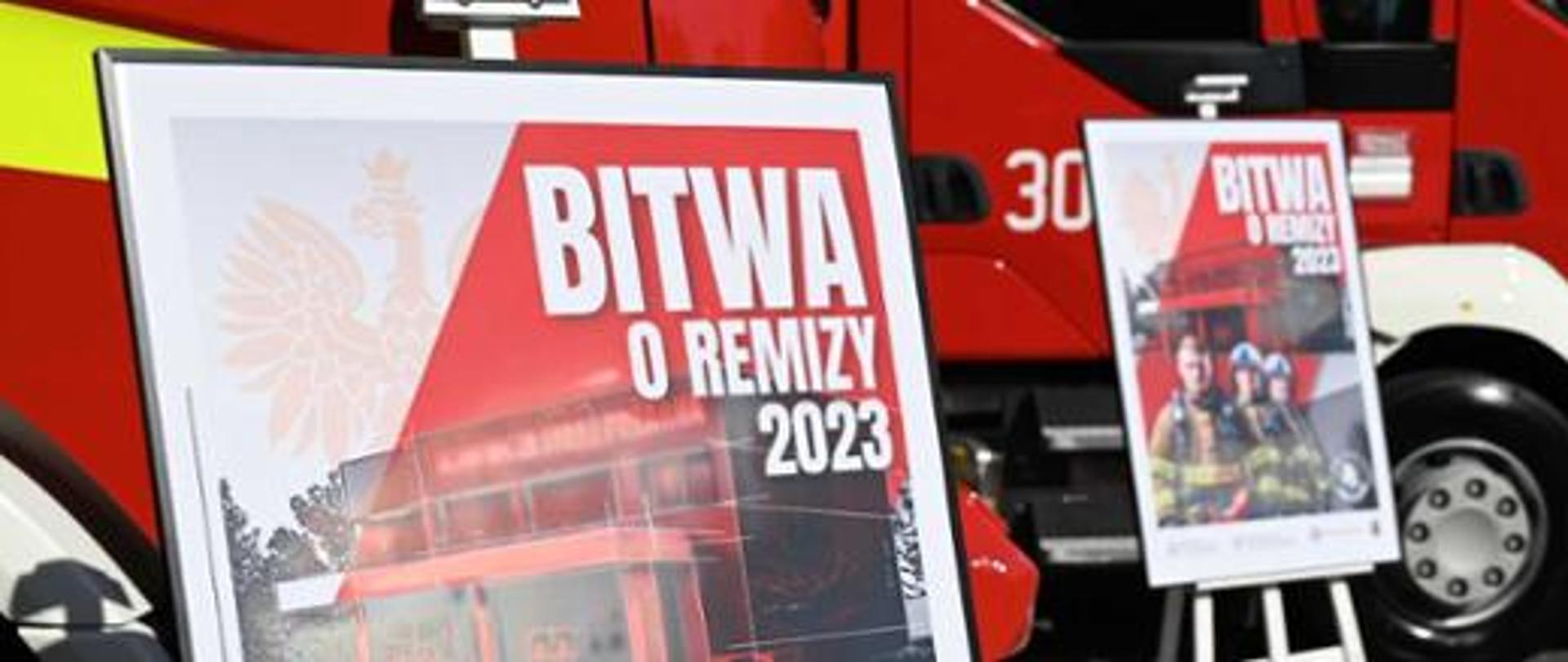 Na zdjęciu baner z napisem Bitwa o remizy 2023 w tle samochodu ratowniczo - gaśniczego 