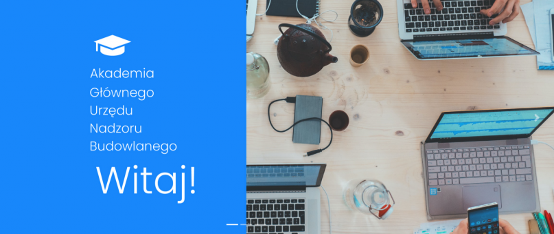 Plansza z napisem „Akademia Głównego Urzędu Nadzoru Budowlanego – Witaj!” oraz widok z góry na stół z trzema laptopami, telefonem, notatnikiem i napojami.