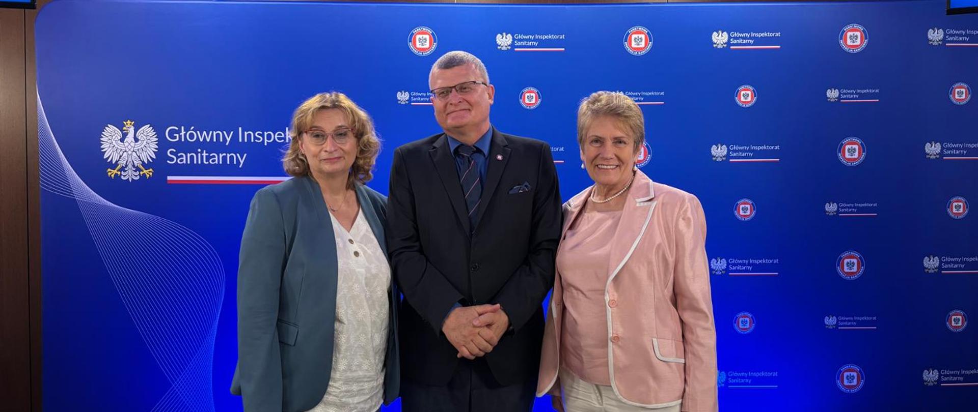 Inspektor Grzesiowski w towarzystwie 2 kobiet na ściance GIS