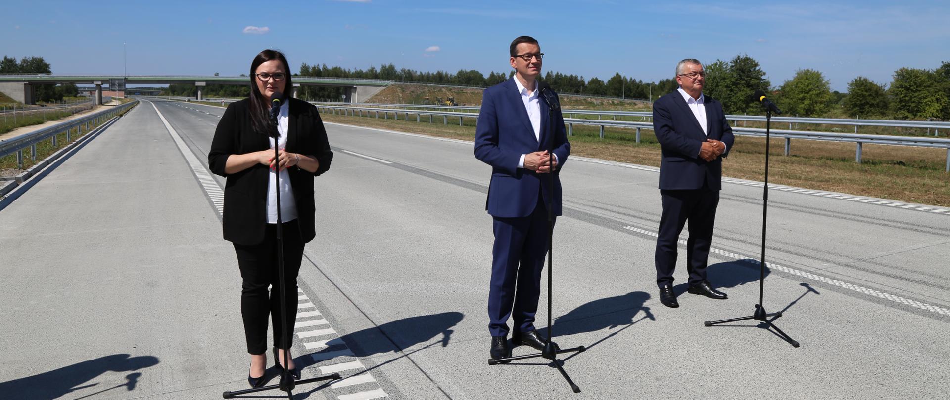 na nowo otwartej autostradzie stoją uczestnicy konferencji od lewej minister Małgorzata Jarosińska-Jedynak, premier Mateusz Morawiecki i minister Andrzej Adamczyk