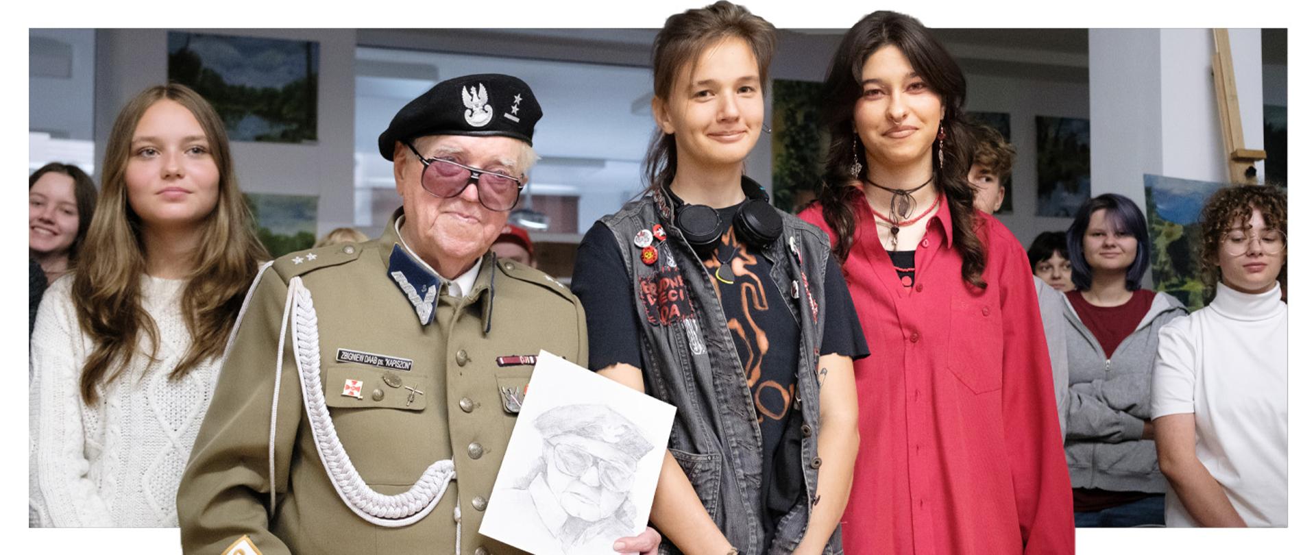 Pan Zbigniew Antoni Daab w towarzystwie uczniów PLSP prezentujący pracę rysunkową stworzoną przez uczennice z klasy 3A po spotkaniu ze społecznością szkolną.
