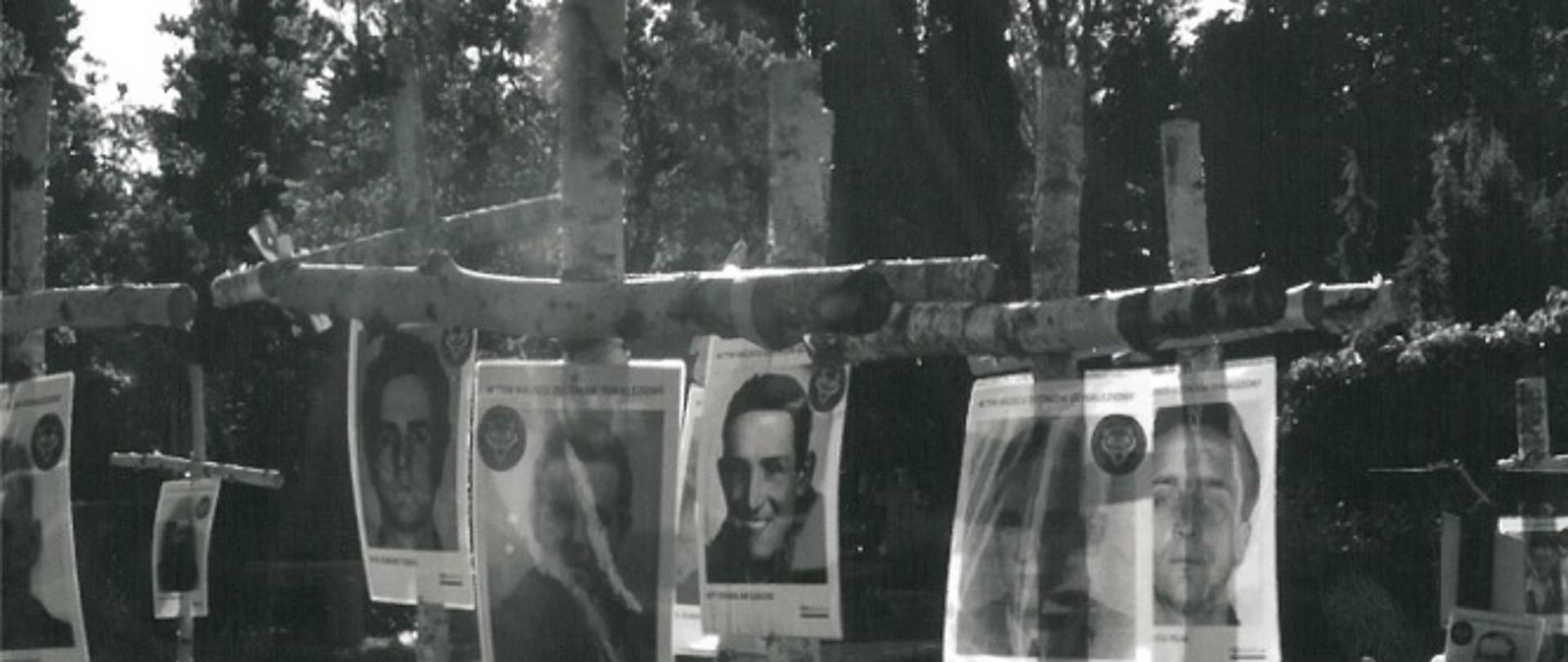 Przedstawia zdjęcia żołnierzy przymocowane do brzozowych krzyży.