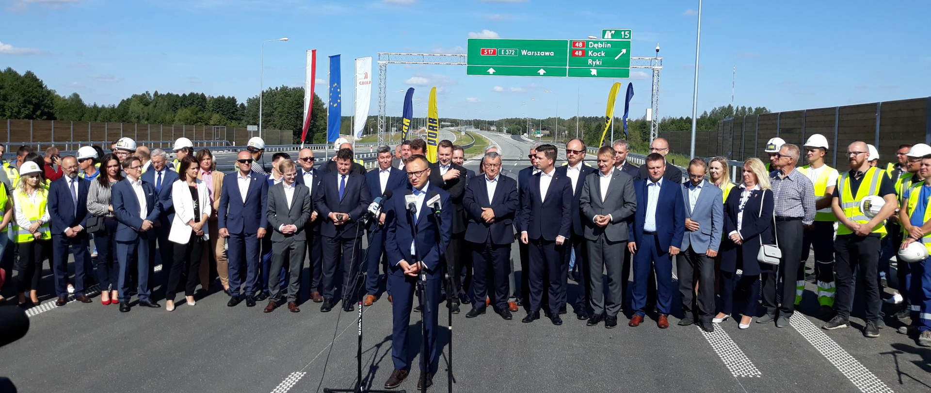 uczestnicy uroczystości stoją, przemawia do mikrofonu wiceminister Artur Soboń