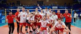 Na środku boiska do siatkówki stoi grupa kilkunastu mężczyzn w biało-czerwonych ubraniach.