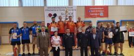 Zdjęcie grupowe, zwycięzcy na podium, przed nimi stoi 2 funkcjonariuszy PSP oraz trzy inne osoby