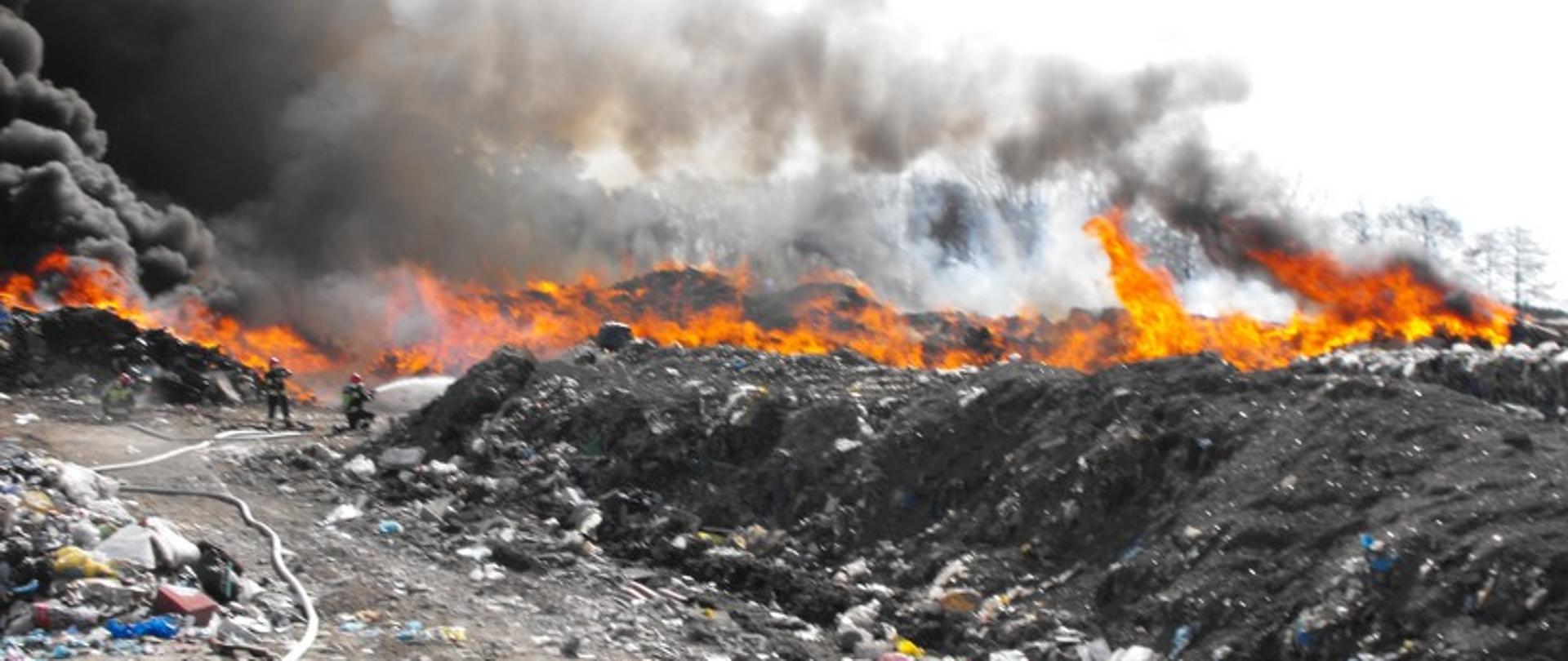 Zdjęcie przedstawia palące się wysypisko śmieci