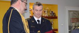Komendant Powiatowy PSP w Gryfinie bryg. Sławomir Michalski wręcza pamiątkową tabliczkę asp. Norbertowi Kubacha