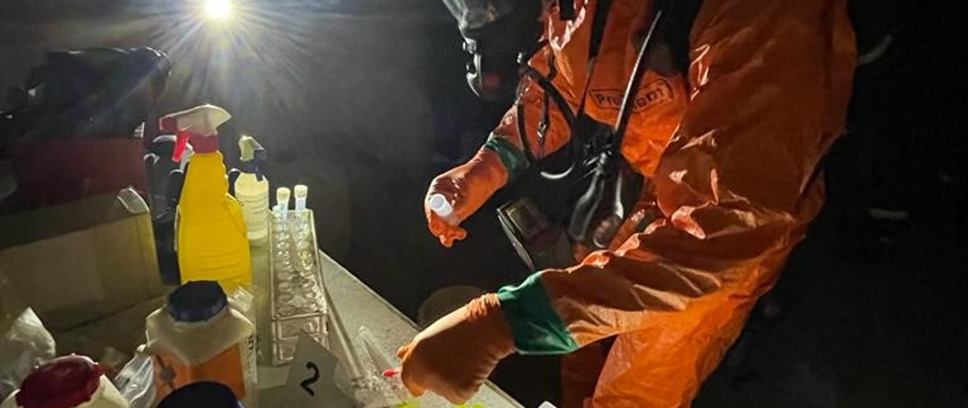 Szkolenie służb mundurowych w zakresie poboru próbek niezidentyfikowanej substancji. Funkcjonariusze Policji wykonują pobór próbek - instruktaż prowadzą strażacy z Jednostki Ratowniczo-Gaśniczej nr 1 w Kędzierzynie-Koźlu. 