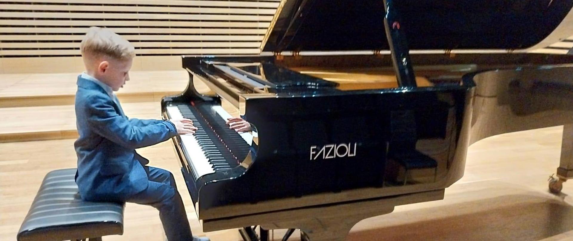 Chłopiec gra na fortepianie.