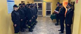 Na korytarzu stoją strażacy podczas zbiórki z okazji ślubowania strażaka.
