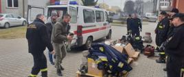 Strażacy OSP z powiatu radomszczańskiego – OSP Gidle rozpakowują sprzęt pożarniczy, który ma być docelowo przekazany ukraińskim strażakom. Na placu KP PSP Radomsko ustawiony sprzęt strażacki na palecie: ubrania specjalne, węże, rozdzielacze, torba medyczna.