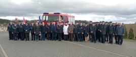 Zdjęcie grupowe uczestników uroczystości na tle wozu strażackiego 