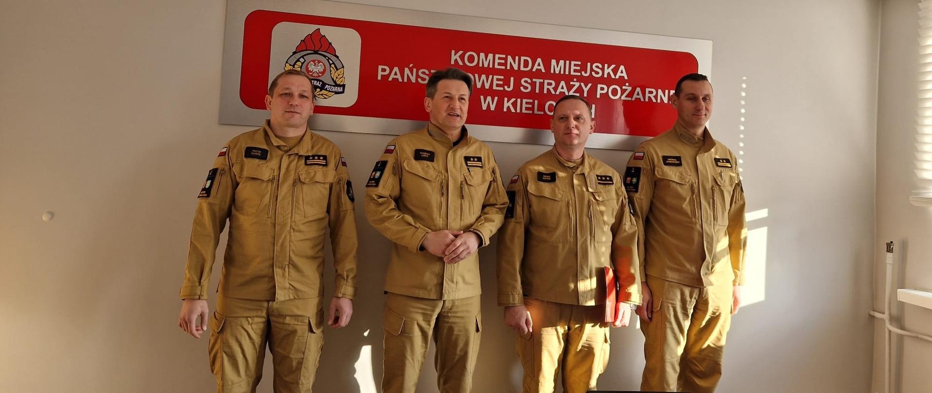 Zdjęcie przedstawia kpt. Adama Kotasia w towarzystwie Komendanta Miejskiego PSP w Kielcach bryg. Mariusza Góry i jego zastępców st. bryg. Piotra Sokóla i bryg. Michała Janowskiego.