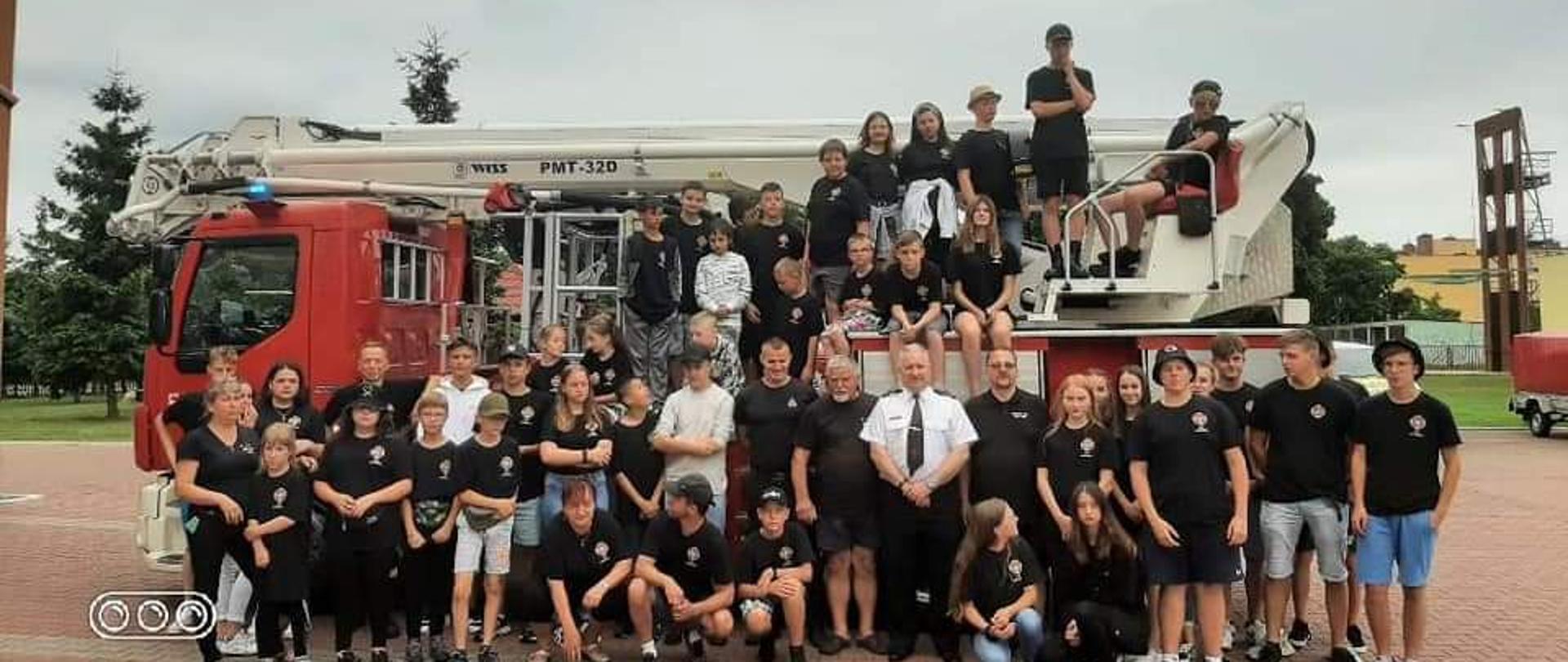 Wspólne zdjęcie członków MDP z Mszany Dolnej wraz z Komendantem Powiatowym w Pile oraz Dowódcą JRG II w Pile tle pojazdu SCHD 30.