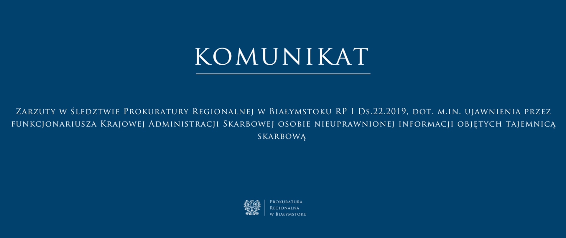 Baner ma ciemnoniebieskie tło i biały tekst, utrzymany w eleganckiej, klasycznej czcionce. W górnej części znajduje się duży napis „KOMUNIKAT” podkreślony cienką białą linią. Poniżej umieszczono treść komunikatu ” Zarzuty w śledztwie Prokuratury Regionalnej w Białymstoku RP I Ds.22.2019, dot. m.in. ujawnienia przez funkcjonariusza Krajowej Administracji Skarbowej osobie nieuprawnionej informacji objętych tajemnicą skarbową” Na dole, pośrodku, znajduje się logo Prokuratury Regionalnej w Białymstoku oraz jej nazwa.