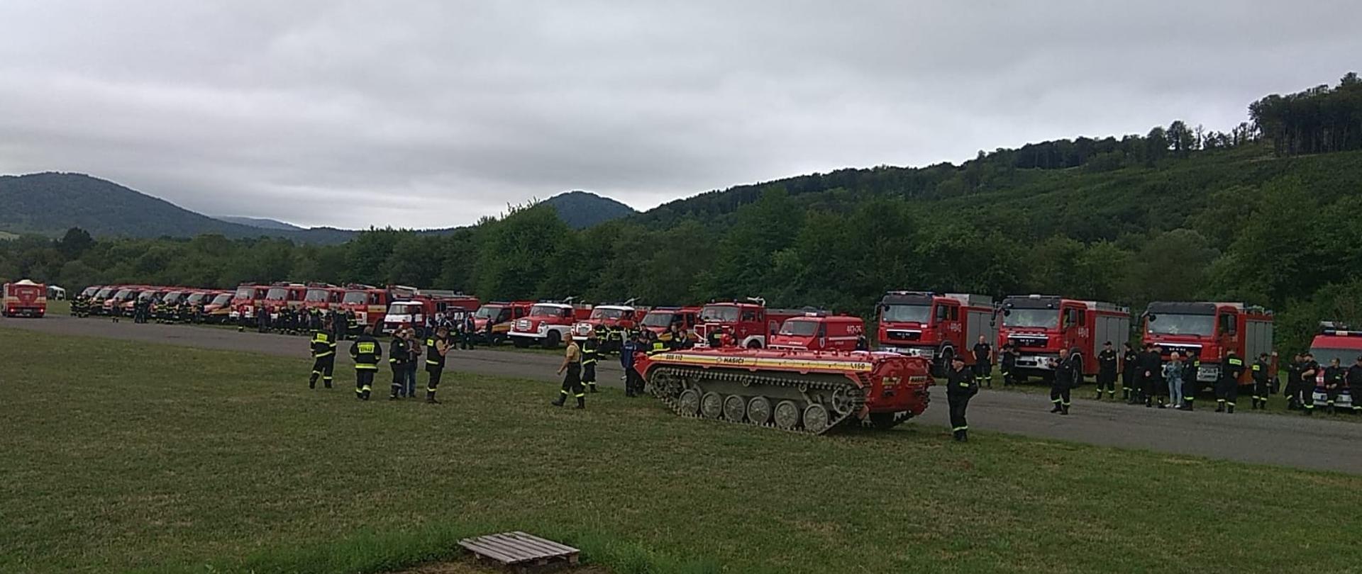 Na zdjęciu strażacy z Polski oraz Słowacji podczas ćwiczeń międzynarodowych pod kryptonimem ZACHARNA 2022. W oddali samochody ratowniczo- gaśnicze polskie i słowackie.
