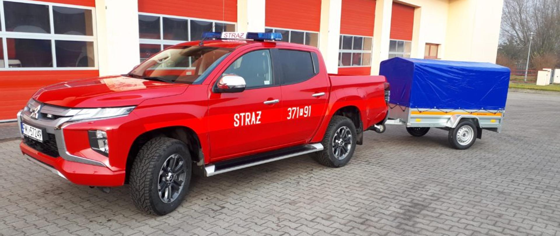 Zdjęcie nowo zakupionego pojazdu typu SLRR Mitsubishi z przyczepką na tle bram garażowych JRG w Międzyrzeczu.