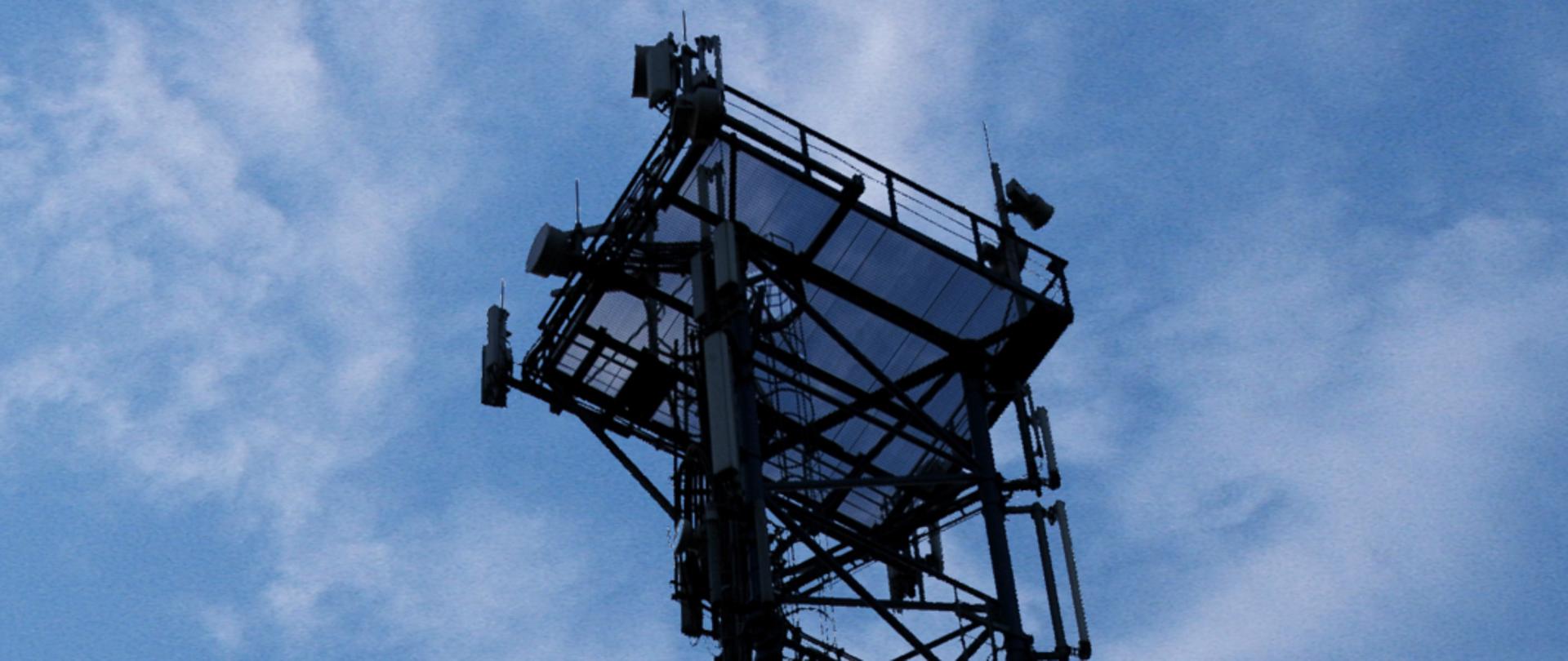 Zdjęcie części masztu telefonii komórkowej z widocznymi antenami LTE i radiolinią.