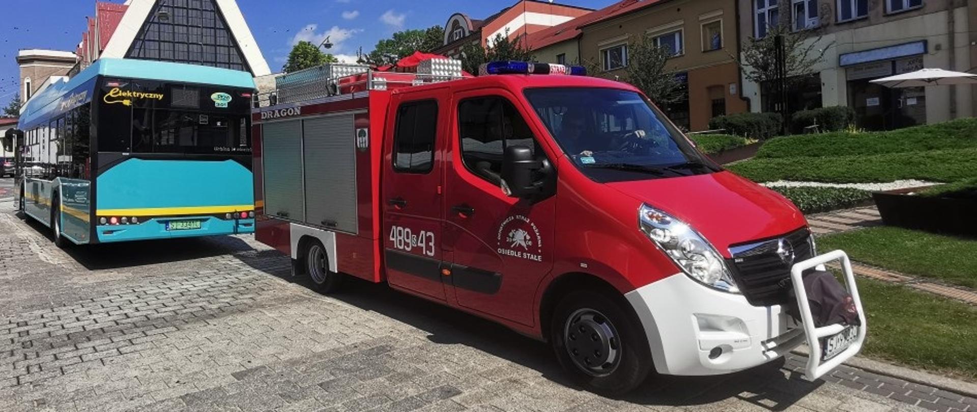 Zdjęcie przedstawia samochód OSP Osiedle Stałe zabezpieczający autobus PKM Jaworzno przeprowadzający szczepienia w mobilnym punkcie przy parafii Św. Wojciecha.