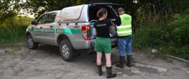 Pracownicy WIOŚ i GIOŚ stojący przy samochodzie laboratorium podczas pobierania próbek wody i ścieków do badań 