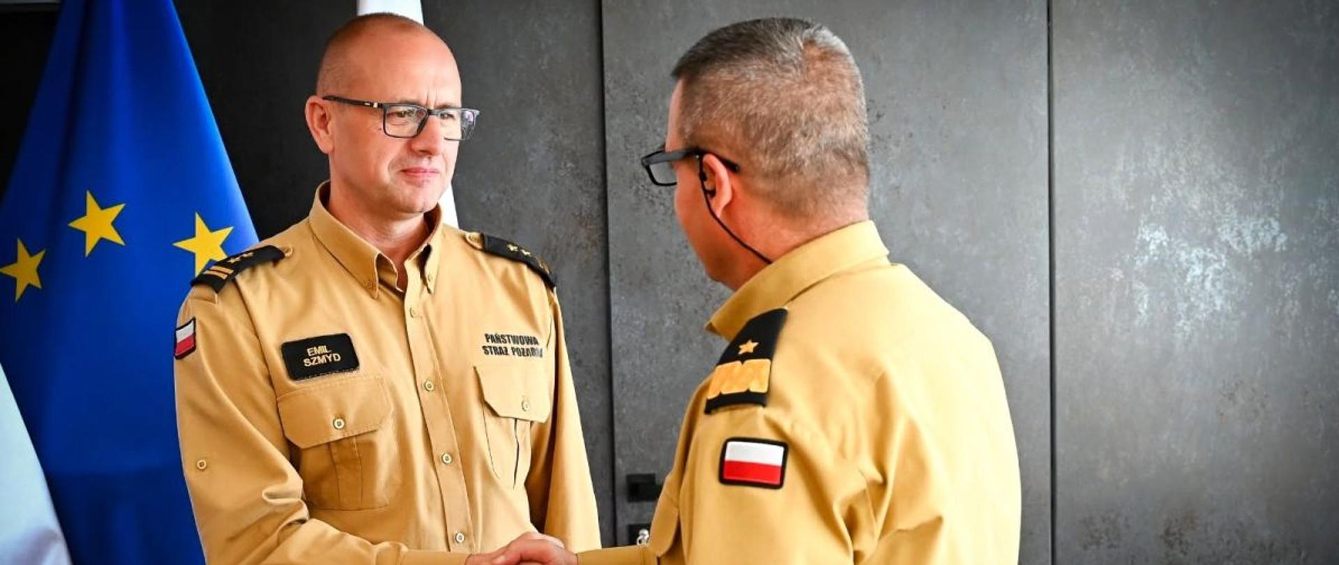 Na zdjęciu komendant wojewódzki i komendant powiatowy w biurze. Komendant powiatowy odbiera gratulacje od komendanta wojewódzkiego. 