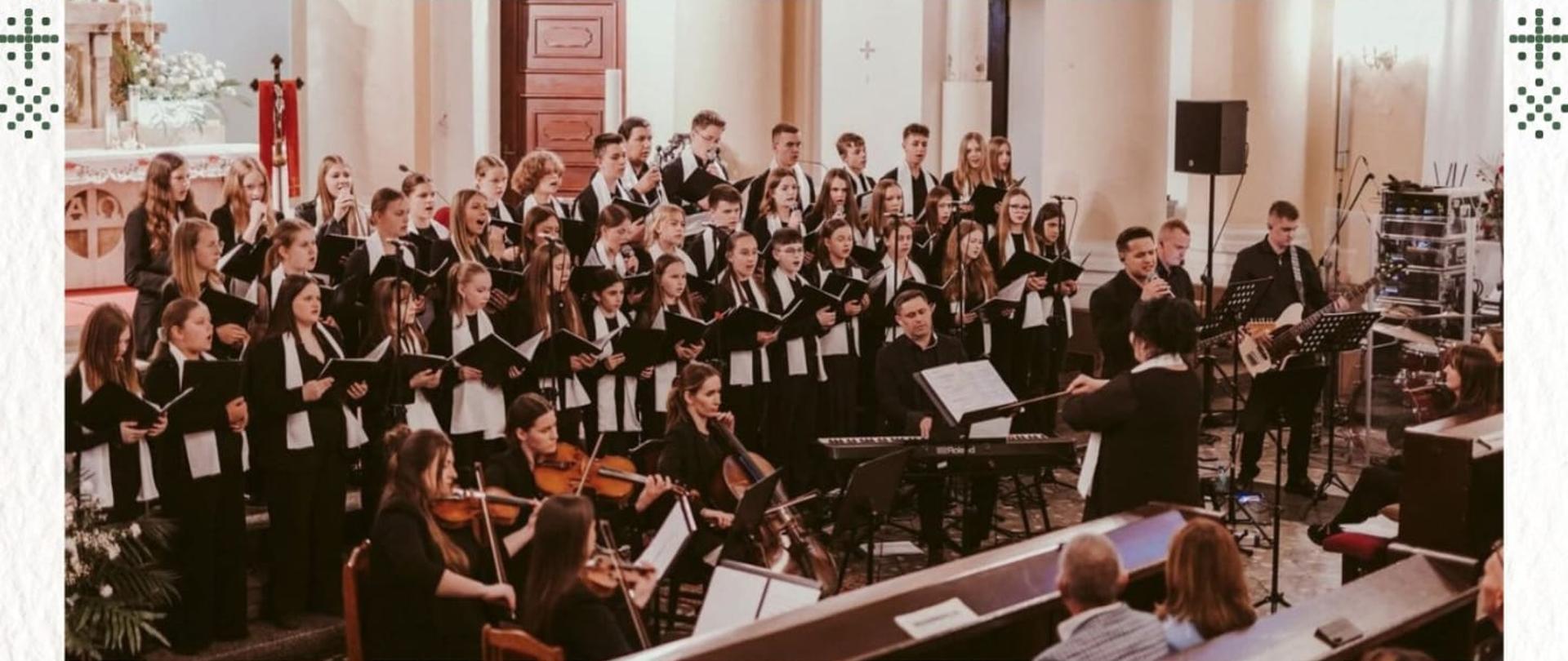 Plakat zapraszający na „Koncert Świąteczny”. Grafika utrzymana w jasnej, zimowo-świątecznej stylistyce, na kremowym tle z delikatnymi zielonymi motywami choinek i śnieżynek. W górnej części znajduje się zdjęcie dużego chóru młodzieżowego i zespołu instrumentalnego występujących w kościele, pod dyrekcją dyrygenta. Poniżej podane są informacje o wykonawcach: Ekipa Dobrego Dźwięku, Chór Con Brio działający przy Państwowej Szkole Muzycznej I stopnia w Kępnie oraz zespół smyczkowy Harmonic Music Team. Po prawej stronie widoczna data i godzina wydarzenia: 25 stycznia, godzina 18:00. Miejscem koncertu jest kościół św. Katarzyny i św. Walentego w Wójcinie. Na dole plakatu znajduje się informacja „Wstęp wolny”.