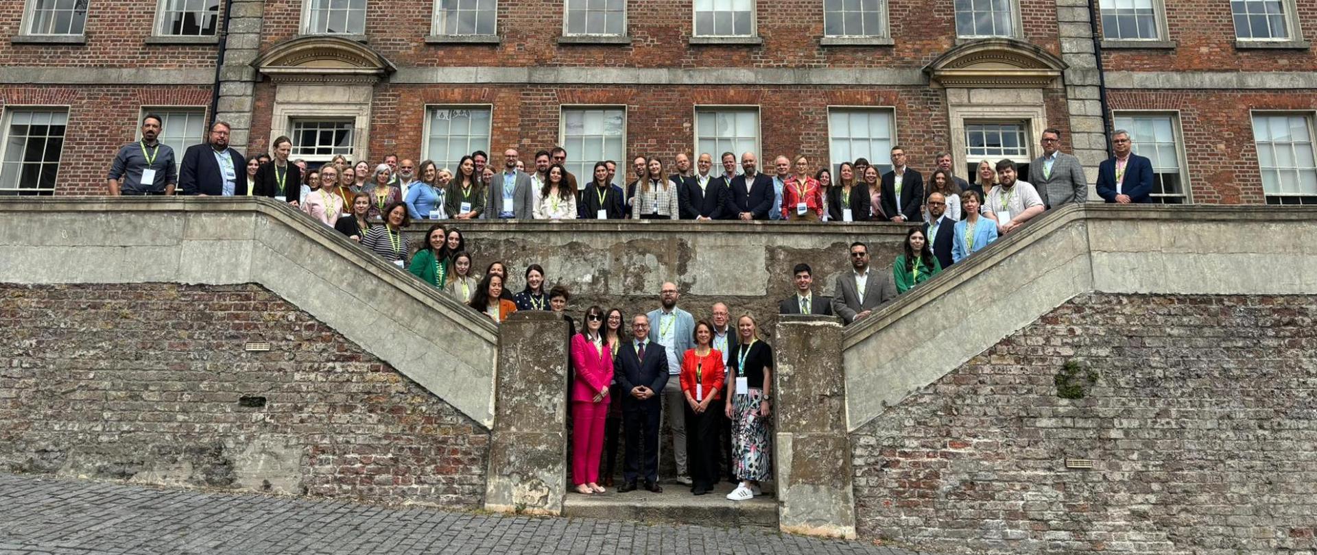 Zdjęcie grupowe przedstawicieli i przedstawicielek krajowych ośrodków koordynacji na schodach przed budynkiem, miejscem spotkania