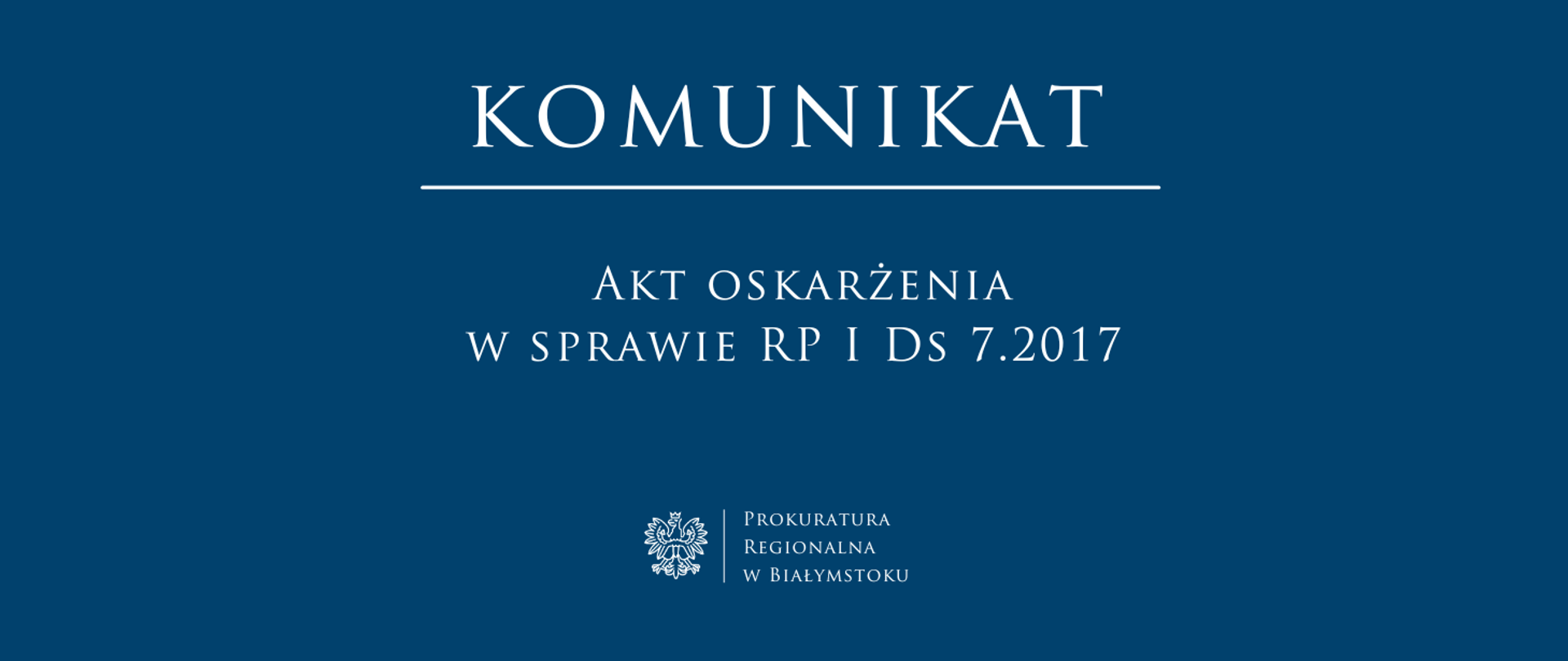To oficjalny baner informacyjny Prokuratury Regionalnej w Białymstoku. Na ciemnoniebieskim tle widnieje duży nagłówek „KOMUNIKAT”, a pod nim informacja o akcie oskarżenia w sprawie oznaczonej „RP I Ds 7.2017”. U dołu umieszczono godło oraz nazwę instytucji, co podkreśla urzędowy charakter grafiki.